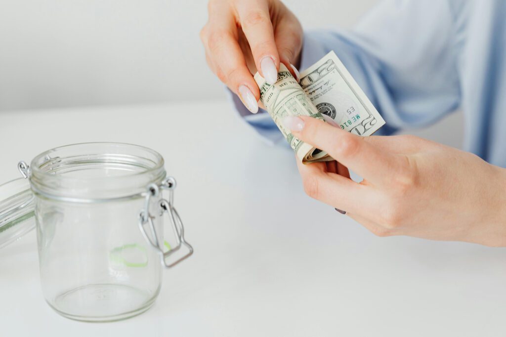 hands putting money in a jar