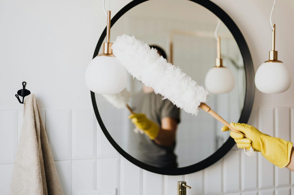 cleaner dusting a mirror