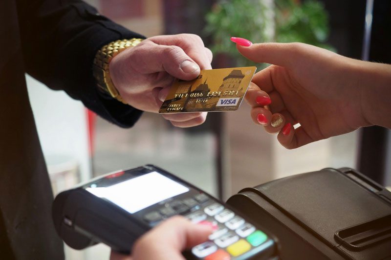 person handing a store clerk a credit card for payment