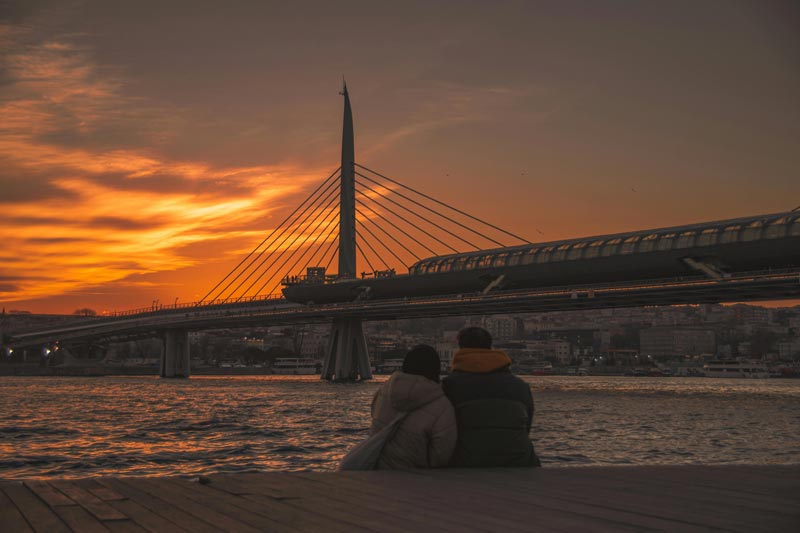 couple bunded up watching the sunset over the water