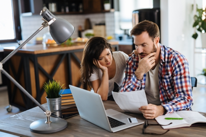 stressed couple reviewing credit card bill on laptop
