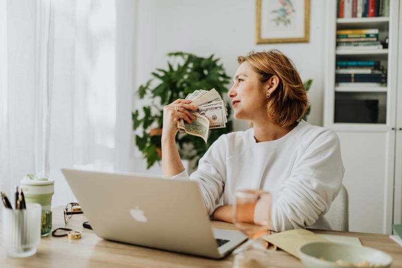 woman at desk with stack of money bills