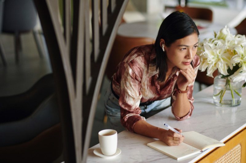 thoughtful woman writing in journal