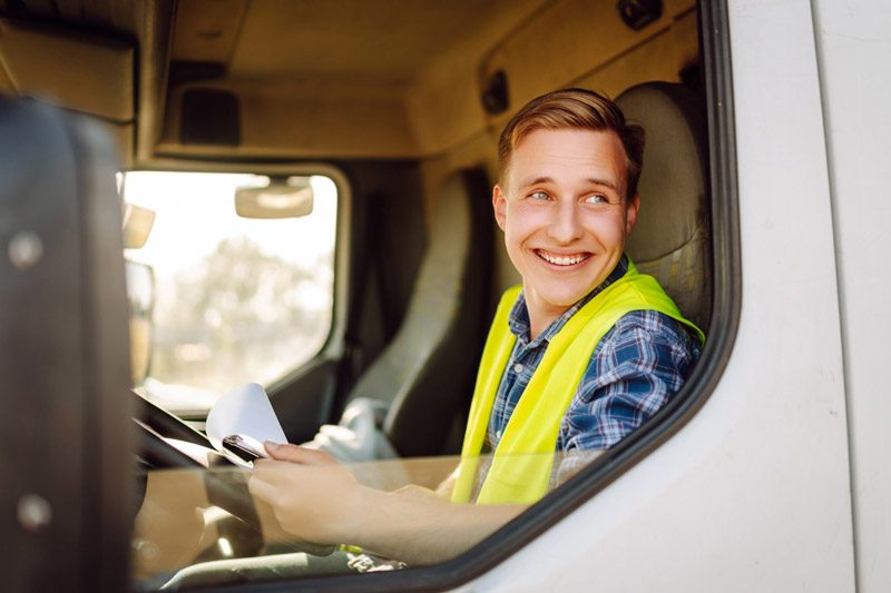 young man smiling out window of delivery truck