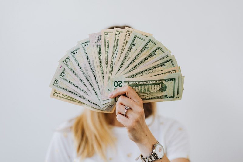 woman holding a fan of $20 bills