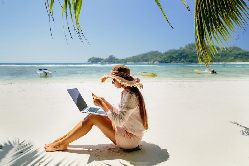woman working on her laptop from the beach