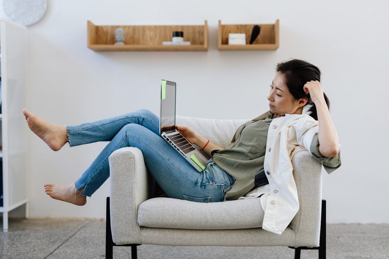 woman working on laptop sitting sideways in chair